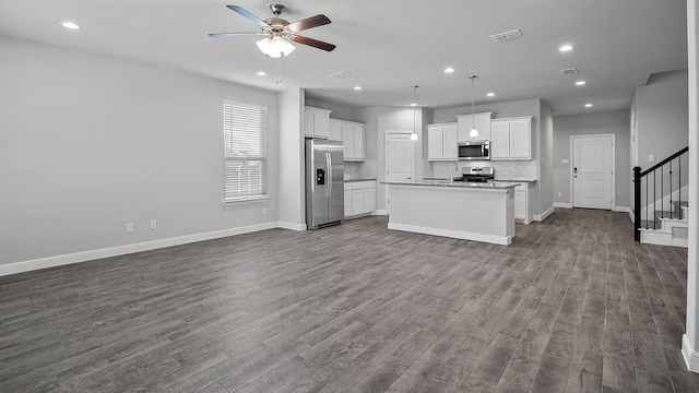 kitchen featuring appliances with stainless steel finishes, hardwood / wood-style floors, a kitchen island with sink, white cabinets, and ceiling fan