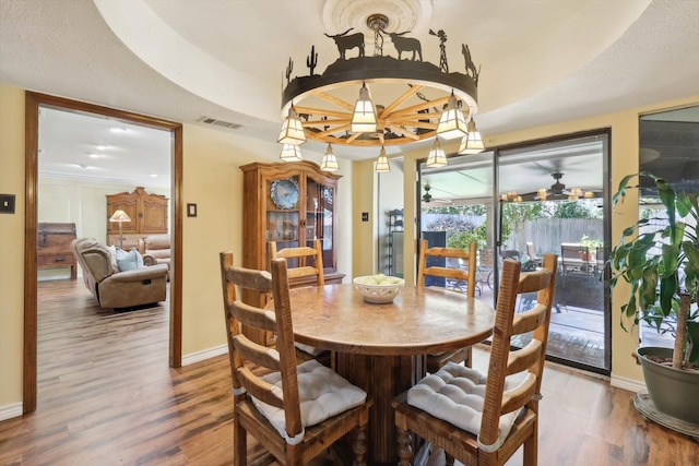 dining room featuring ceiling fan, hardwood / wood-style flooring, and a tray ceiling