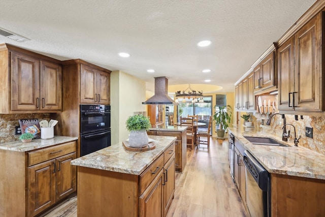 kitchen with light hardwood / wood-style flooring, a kitchen island, wall chimney exhaust hood, sink, and double oven