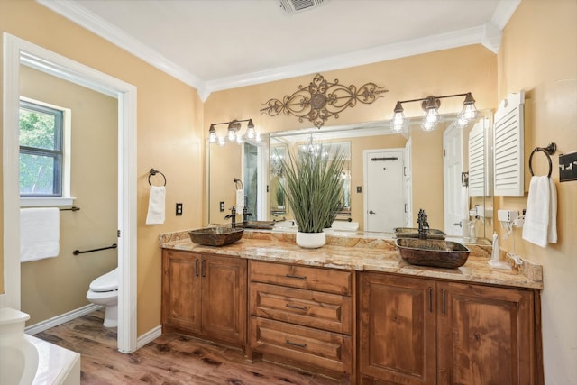 bathroom with ornamental molding, hardwood / wood-style flooring, dual bowl vanity, a bathing tub, and toilet