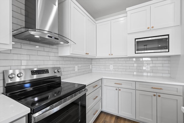 kitchen featuring wall chimney exhaust hood, white cabinetry, and appliances with stainless steel finishes