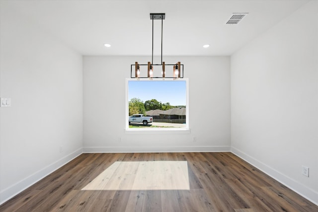 unfurnished dining area with an inviting chandelier and dark wood-type flooring