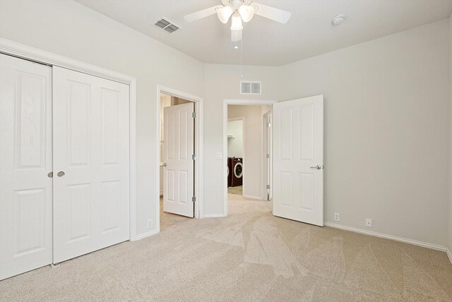 unfurnished bedroom featuring a closet, washer / dryer, light colored carpet, and ceiling fan