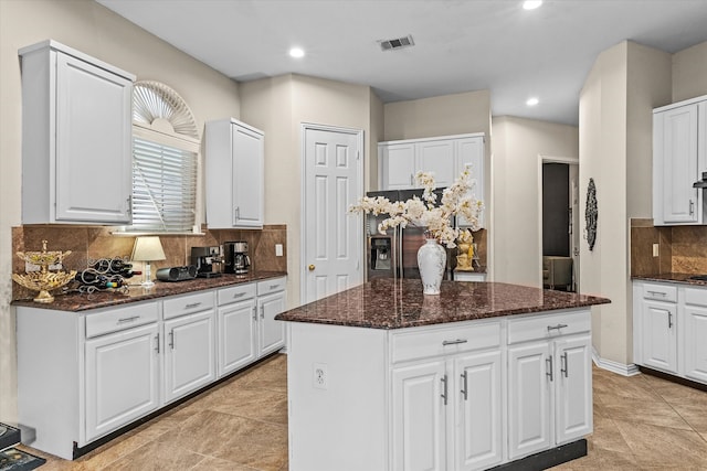 kitchen with a kitchen island, white cabinetry, light tile patterned floors, and tasteful backsplash