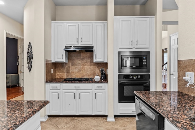 kitchen with white cabinetry, dark stone countertops, light tile patterned flooring, and black appliances