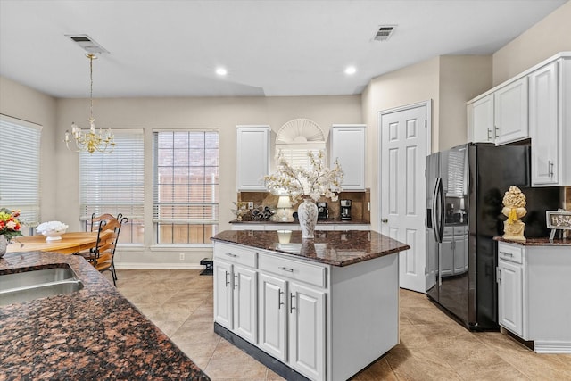 kitchen with hanging light fixtures, visible vents, white cabinets, and black fridge with ice dispenser