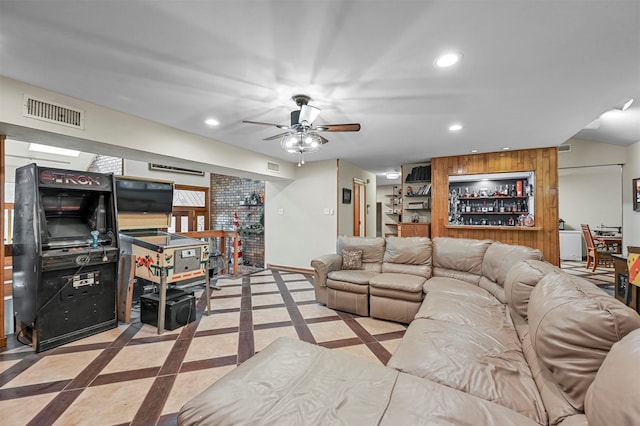 living room with ceiling fan, light tile patterned floors, and brick wall