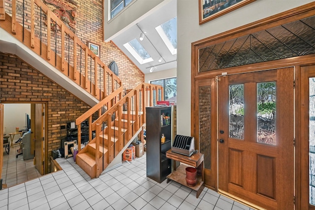 tiled foyer entrance featuring beam ceiling, high vaulted ceiling, a skylight, and plenty of natural light