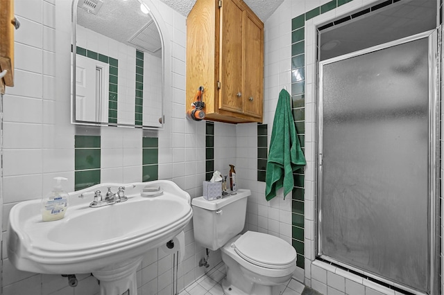 bathroom featuring tile patterned flooring, tile walls, a textured ceiling, and walk in shower