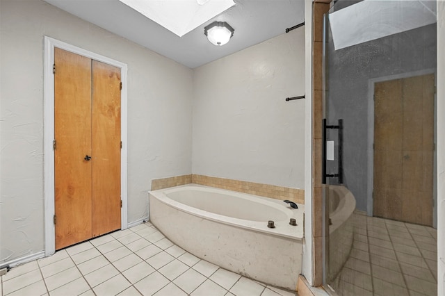 bathroom featuring tile patterned flooring, a bathing tub, and a skylight