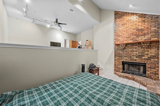 unfurnished bedroom with ceiling fan, track lighting, a brick fireplace, and lofted ceiling