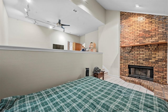 unfurnished bedroom with a fireplace, vaulted ceiling, ceiling fan, light tile patterned floors, and rail lighting