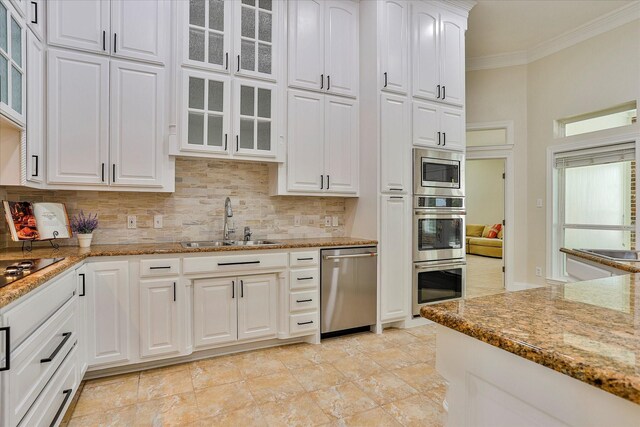 kitchen featuring appliances with stainless steel finishes, white cabinetry, stone counters, tasteful backsplash, and sink