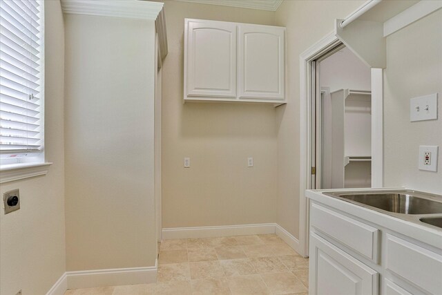 washroom with hookup for an electric dryer, light tile patterned floors, ornamental molding, and cabinets