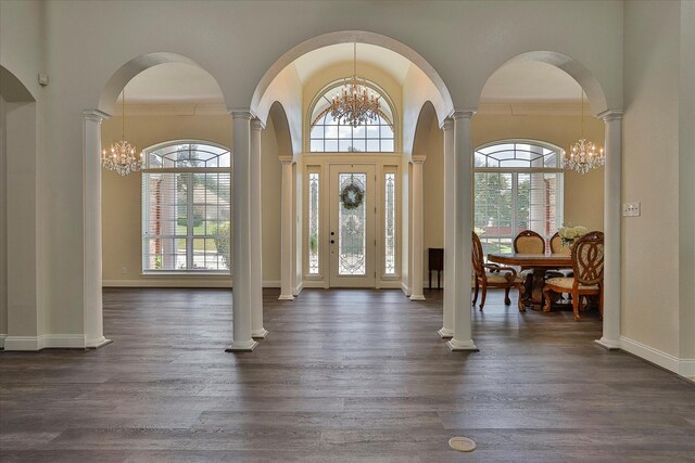 entrance foyer featuring ornate columns, a notable chandelier, a healthy amount of sunlight, and dark wood-type flooring