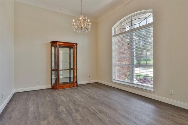 spare room with hardwood / wood-style floors, a wealth of natural light, crown molding, and an inviting chandelier