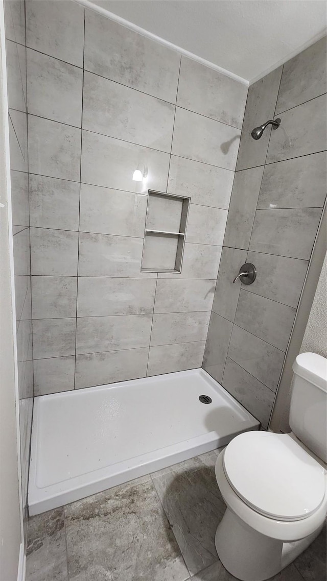 bathroom with toilet and a tile shower