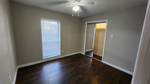 unfurnished bedroom with hardwood / wood-style flooring, a closet, a spacious closet, and ceiling fan