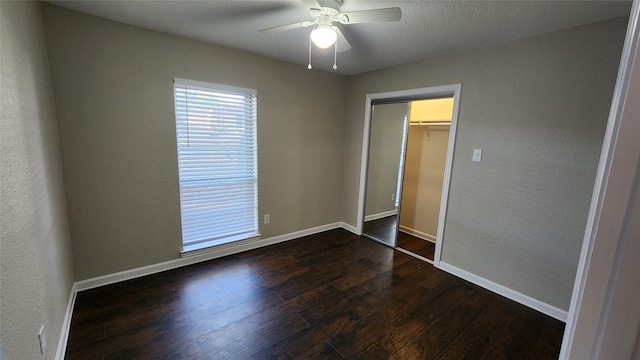 unfurnished bedroom featuring ceiling fan, a textured ceiling, dark hardwood / wood-style flooring, and a closet