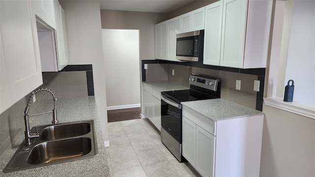 kitchen featuring white cabinets, light wood-type flooring, appliances with stainless steel finishes, and tasteful backsplash