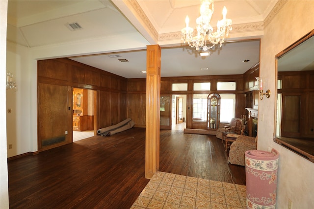 foyer with crown molding, a chandelier, decorative columns, dark wood-type flooring, and wood walls