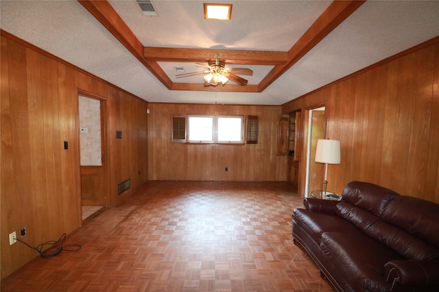 living room featuring ceiling fan, wooden walls, and a textured ceiling