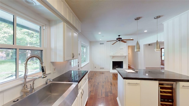 kitchen with dark hardwood / wood-style floors, brick wall, a fireplace, white cabinets, and ceiling fan