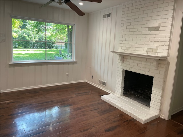 unfurnished living room featuring dark hardwood / wood-style flooring, plenty of natural light, a brick fireplace, and ceiling fan