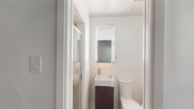 bathroom with tile walls, toilet, and vanity