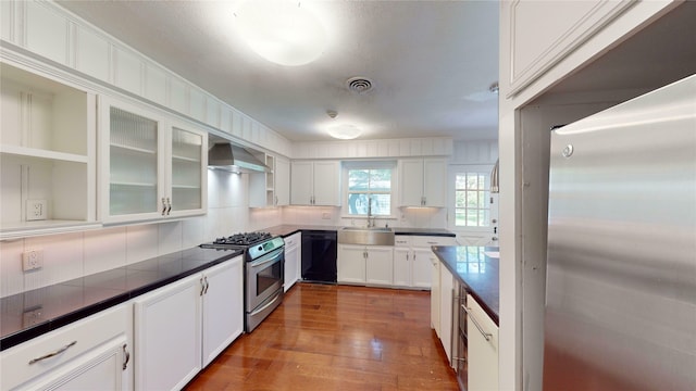 kitchen featuring wall chimney range hood, white cabinets, light hardwood / wood-style floors, sink, and stainless steel appliances