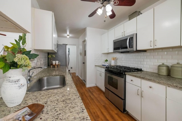 kitchen with white cabinets, sink, hardwood / wood-style flooring, appliances with stainless steel finishes, and tasteful backsplash