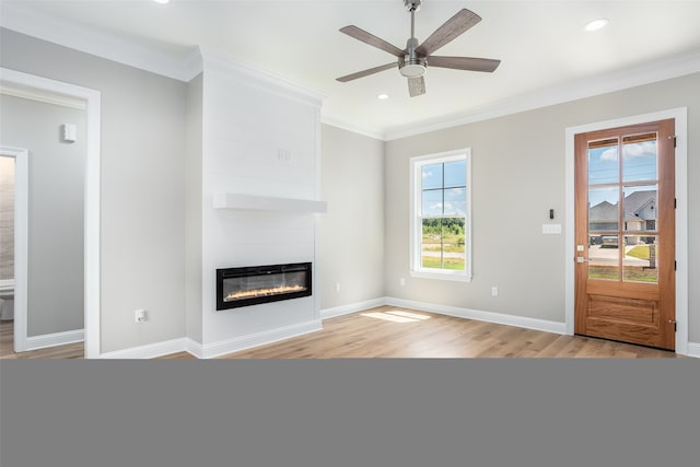 unfurnished living room featuring ceiling fan, light hardwood / wood-style flooring, a large fireplace, and ornamental molding