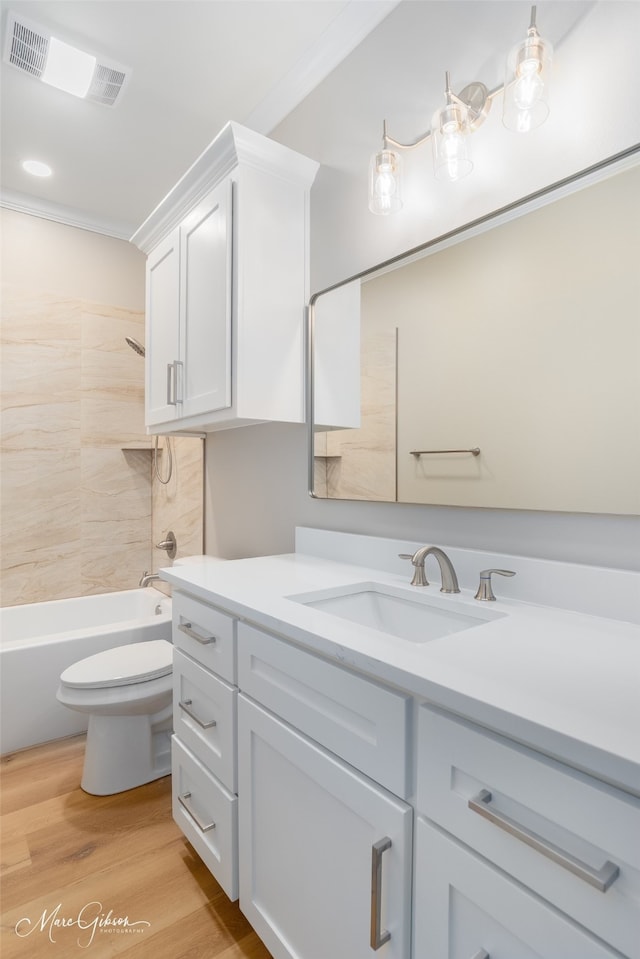 full bathroom featuring crown molding, hardwood / wood-style floors, tiled shower / bath combo, and vanity