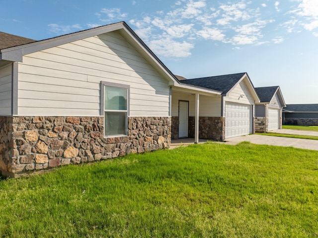 exterior space with a garage, a front yard, stone siding, and driveway