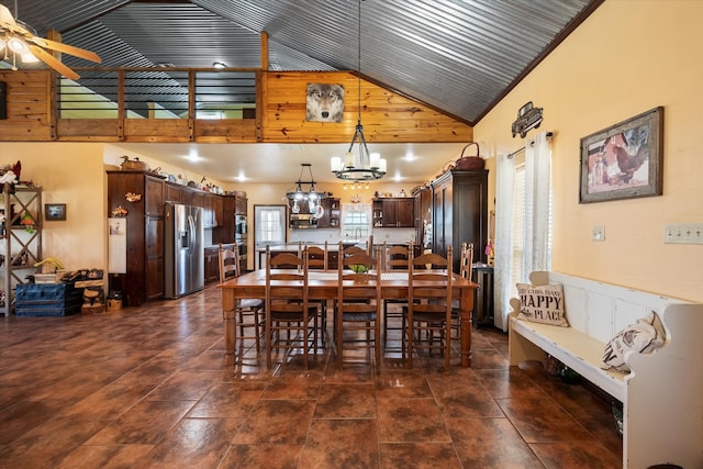 dining room with ceiling fan with notable chandelier, wooden walls, and high vaulted ceiling