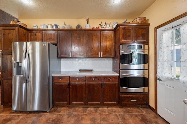 kitchen with light stone countertops, a textured ceiling, appliances with stainless steel finishes, and decorative backsplash