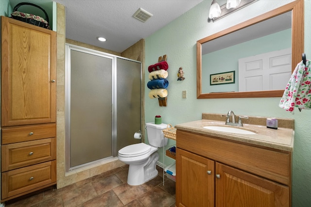 bathroom featuring a textured ceiling, a shower with door, toilet, and vanity