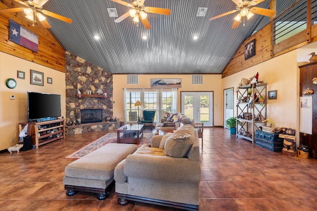 living room with ceiling fan, a stone fireplace, and high vaulted ceiling