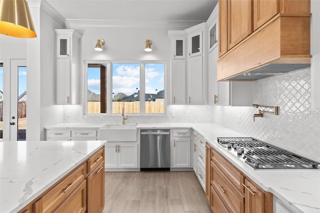 kitchen with white cabinets, custom exhaust hood, stainless steel appliances, backsplash, and crown molding