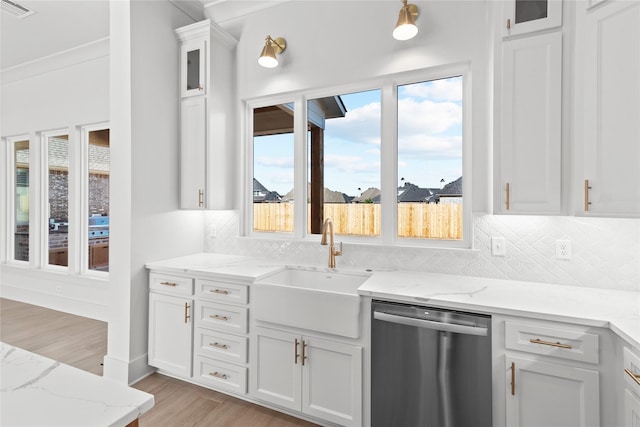 kitchen featuring white cabinetry, light stone countertops, stainless steel dishwasher, light hardwood / wood-style flooring, and sink