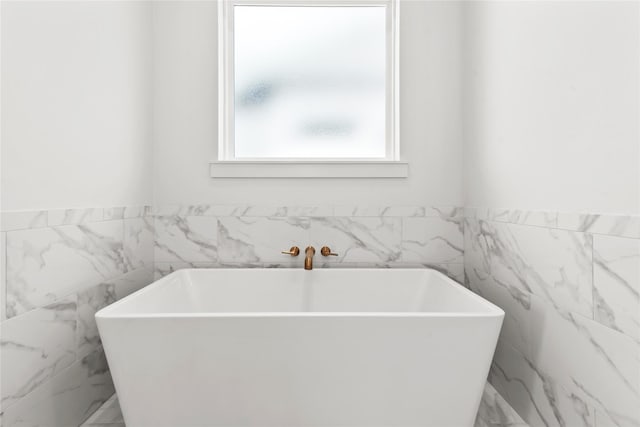 bathroom featuring tile walls and a bath