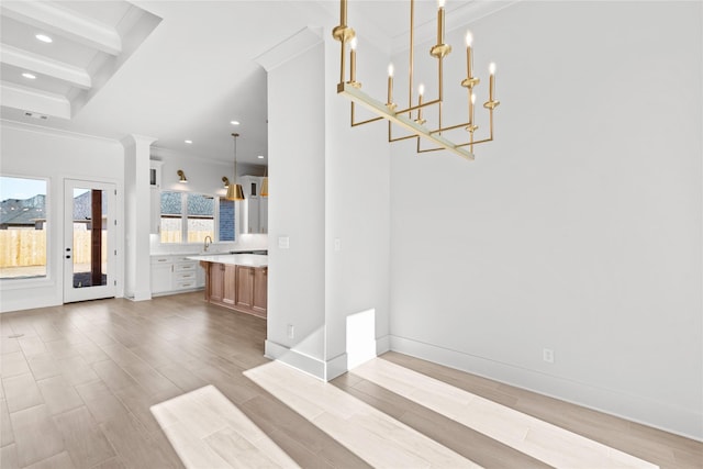 unfurnished dining area with a chandelier, crown molding, beam ceiling, and light hardwood / wood-style flooring