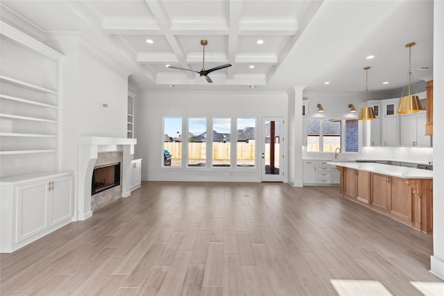 unfurnished living room with a tile fireplace, beamed ceiling, crown molding, coffered ceiling, and built in shelves