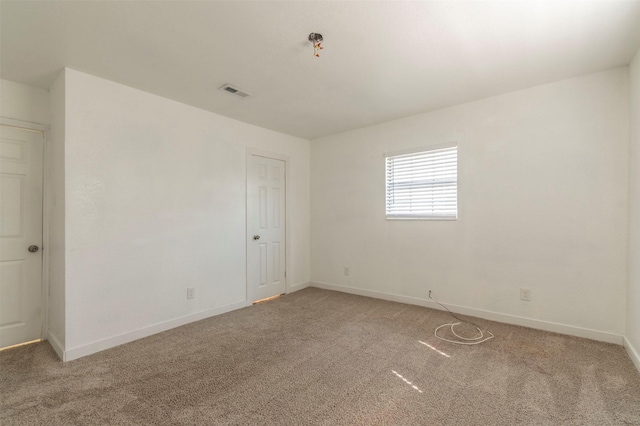 carpeted spare room with visible vents and baseboards