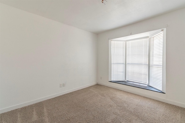 unfurnished room featuring carpet and baseboards