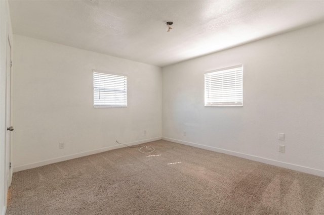 empty room with a textured ceiling, carpet flooring, and baseboards