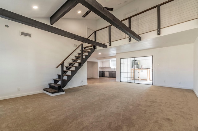 unfurnished living room with high vaulted ceiling, light colored carpet, visible vents, baseboards, and beamed ceiling