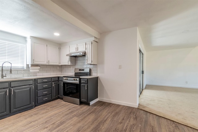 kitchen featuring white cabinets, stainless steel electric range oven, light countertops, under cabinet range hood, and a sink