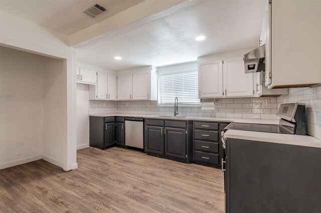 kitchen featuring stainless steel appliances, hardwood / wood-style floors, white cabinetry, decorative backsplash, and sink