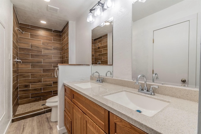 full bath featuring wood finished floors, a sink, toilet, and double vanity